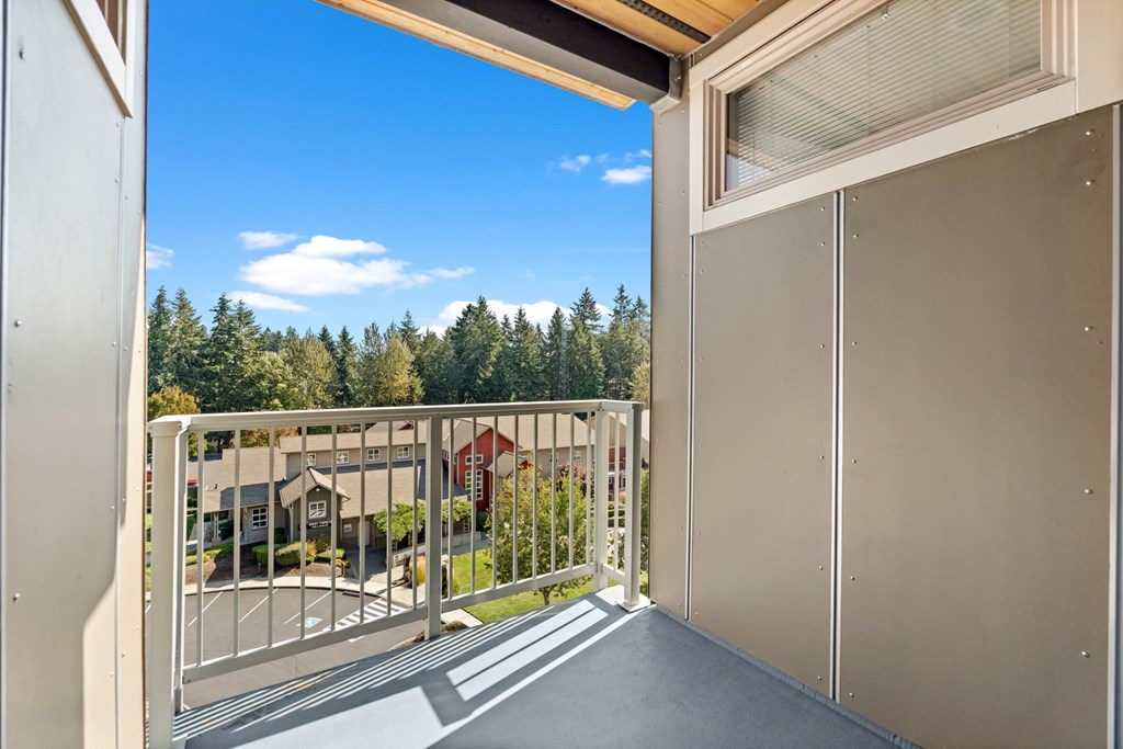 A balcony with a metal railing overlooks a residential area.