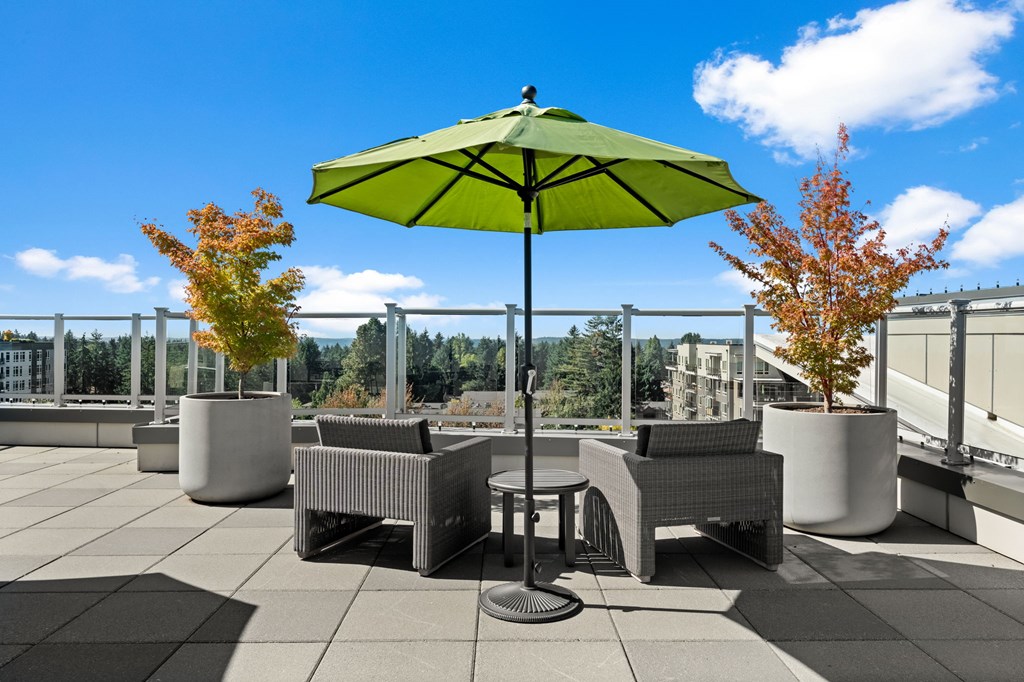 A patio with a table, chairs, and a green umbrella.