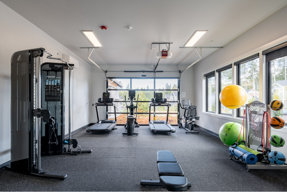 a gym with weights and cardio equipment in a room with windows