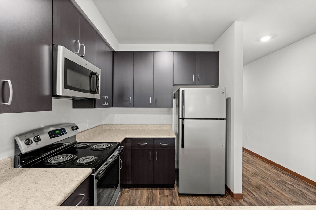 A kitchen with a stove, microwave, and refrigerator.