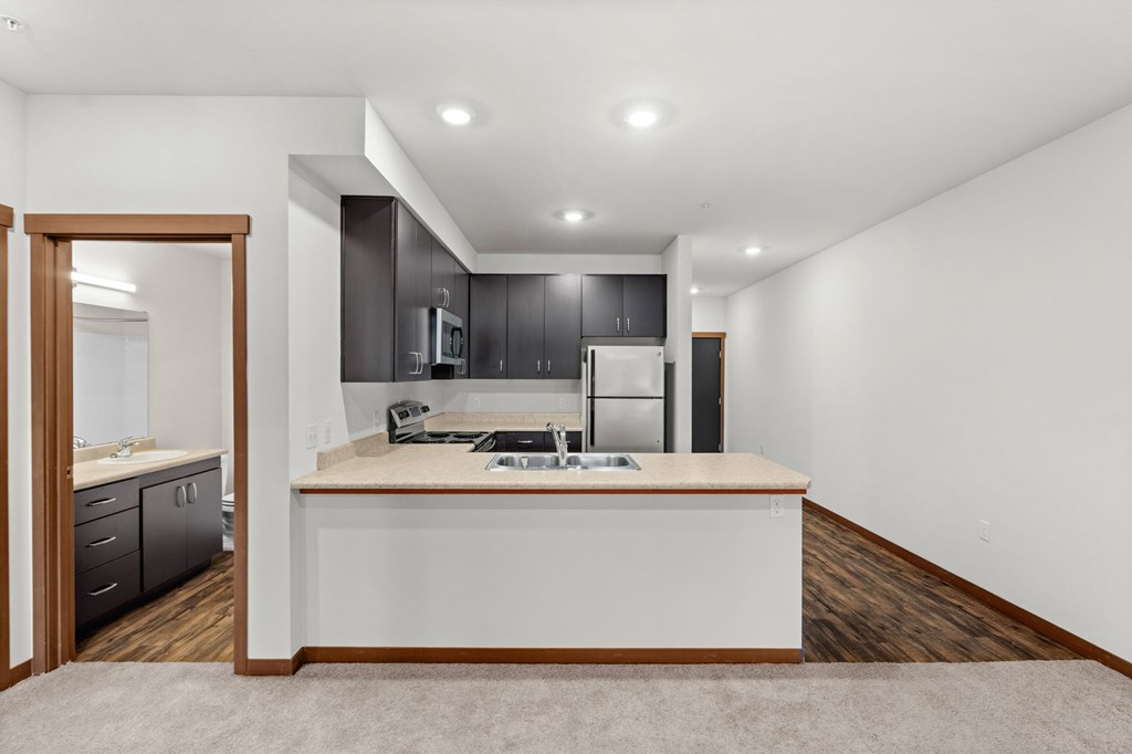 A modern kitchen with a white island and dark wood cabinets.