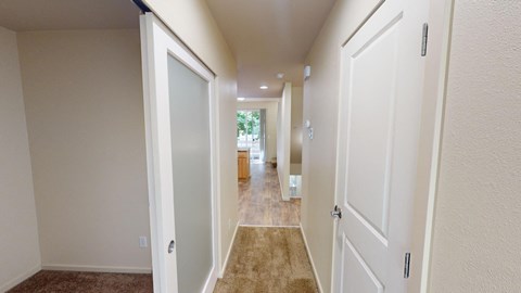 a long hallway with white doors and carpeted floors
