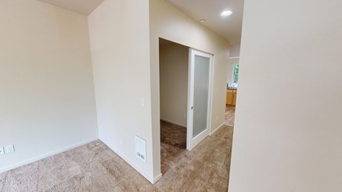 a living room with a carpeted floor and a door to a hallway