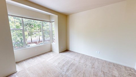 an empty room with a large window and carpet