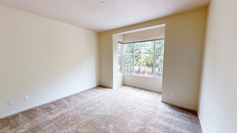 an empty living room with a large window and carpet
