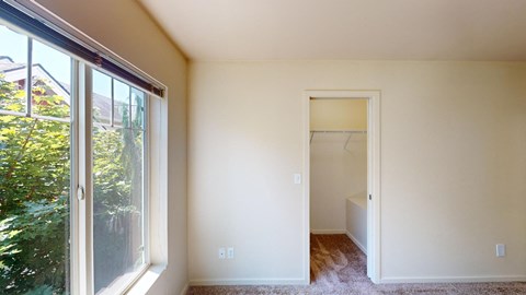 a bedroom with a large window and a door to a closet