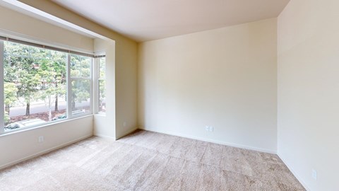 an empty room with a large window and carpet