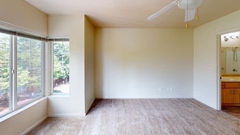 an empty living room with a large window and a ceiling fan