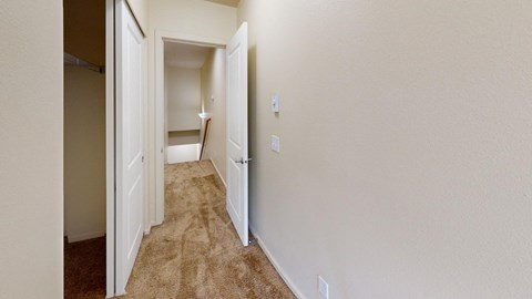 a bedroom with a door open to a hallway with a carpeted floor