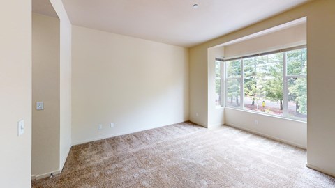 an empty living room with a large window and carpet