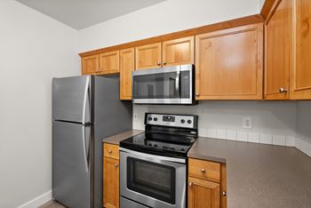 A kitchen with a stainless steel refrigerator, microwave, oven, and cabinets.