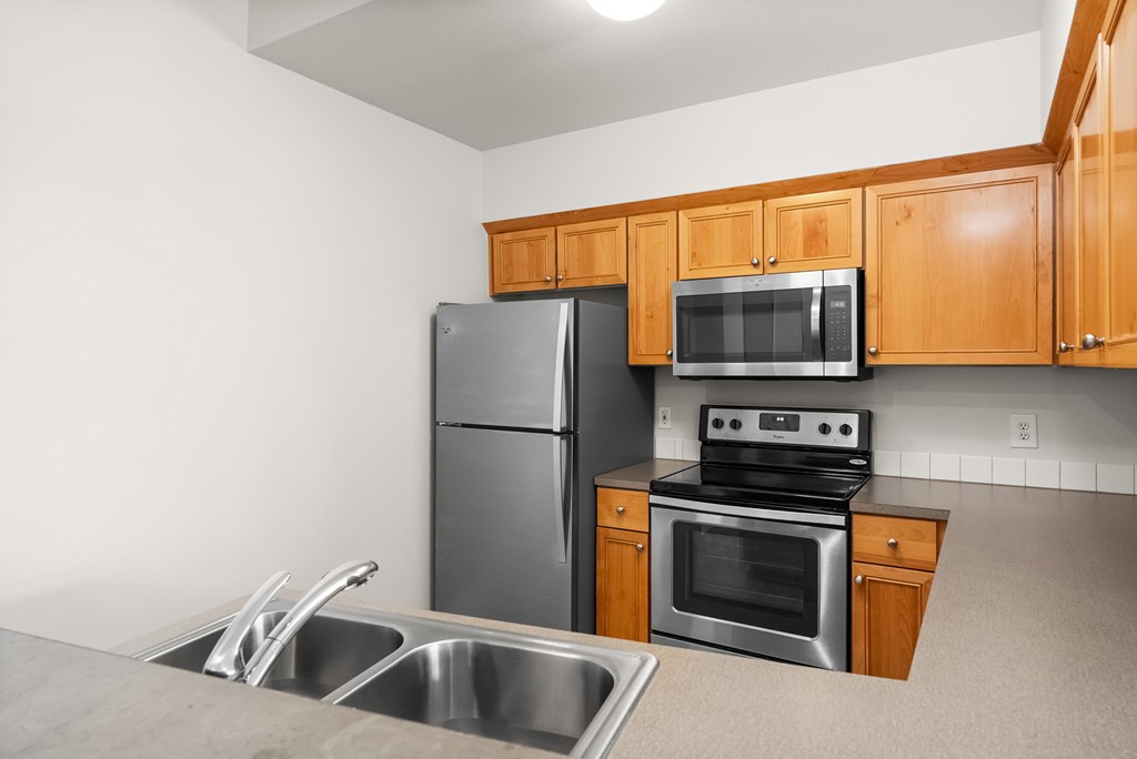 A kitchen with a stainless steel refrigerator, microwave, and oven.