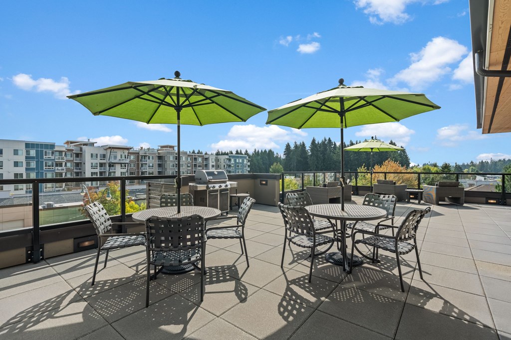 A patio with two tables and chairs under green umbrellas.