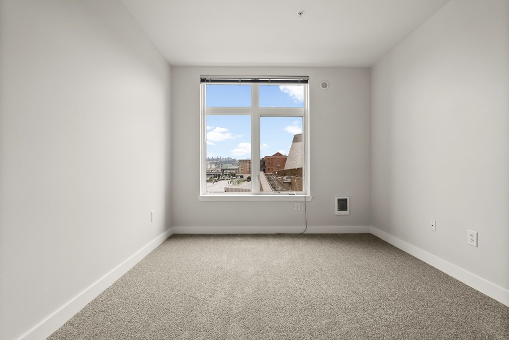 A large empty room with a window overlooking a cityscape.