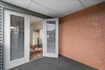 A room with a brick wall and a glass door leading to another room.
