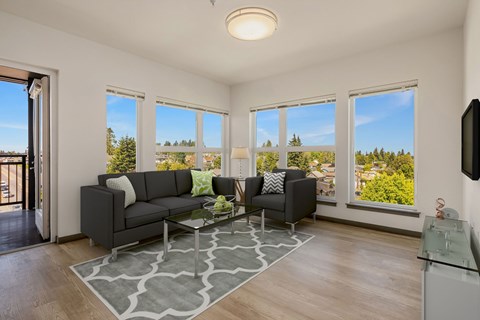 A living room with a grey sofa and a glass coffee table.