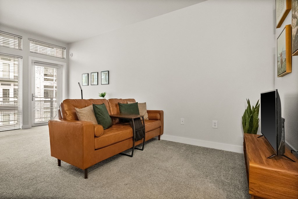 A living room with a brown couch and a television on a wooden stand.