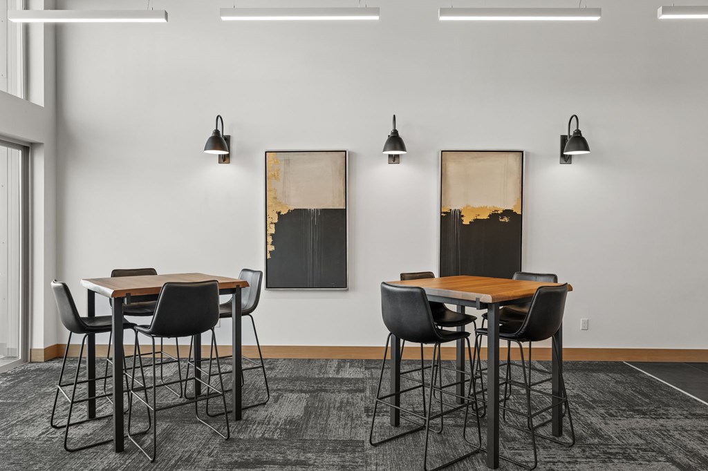 A conference room with a table and chairs and two paintings on the wall.