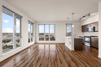 A spacious kitchen and living room with wooden floors and large windows.