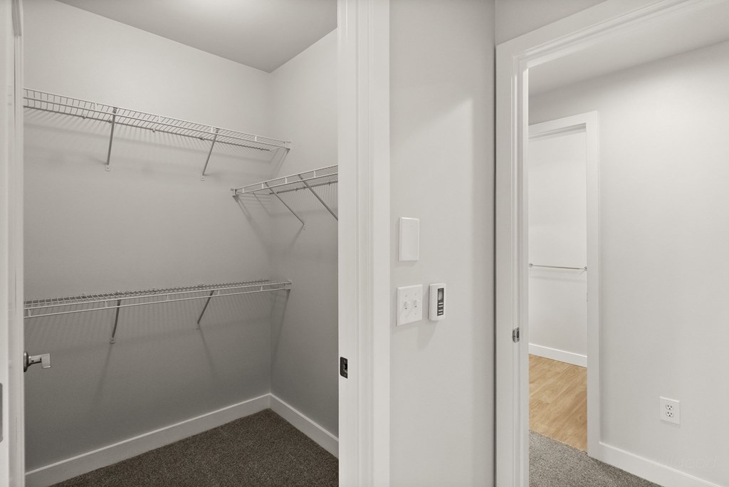 A white closet with a door on the left and an open door on the right.