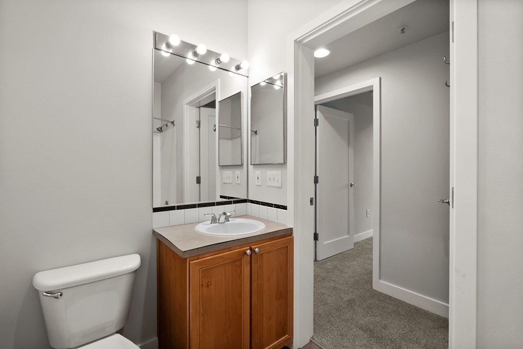 A bathroom with a white toilet, sink, and mirror.