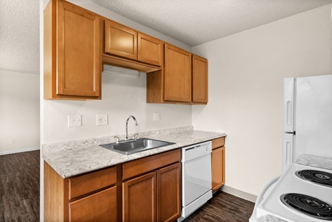 a kitchen with white appliances and wooden cabinets and a sink and counter top