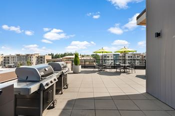 A patio with grills and chairs overlooking a cityscape.