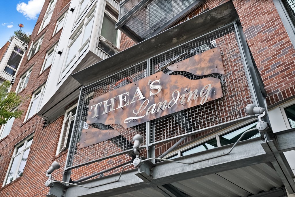 A sign for Thea's Lounge is displayed on a building.