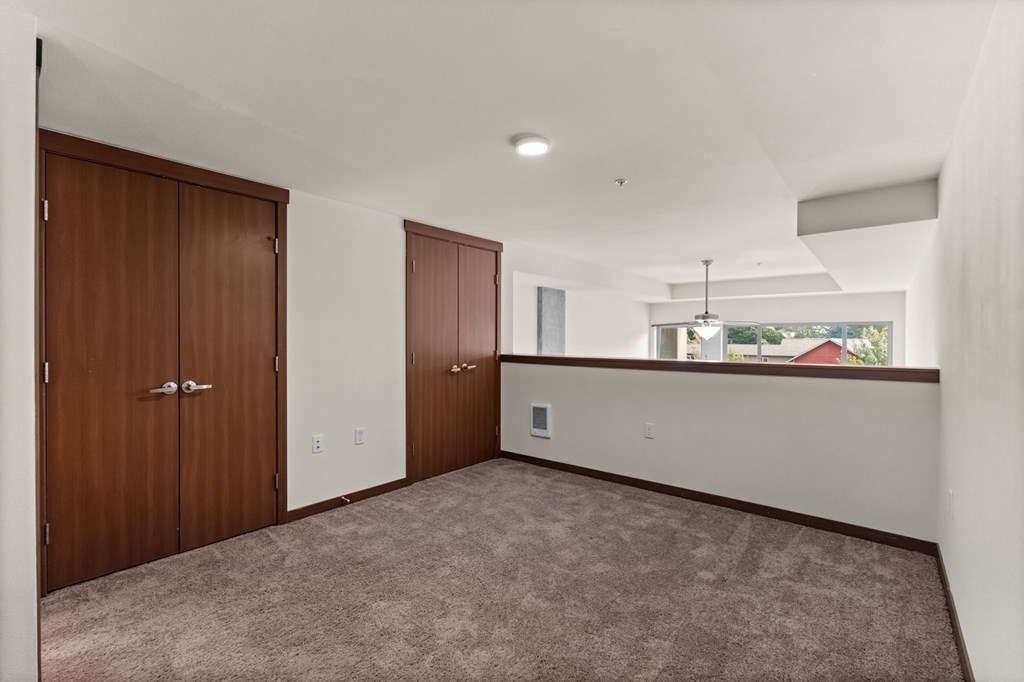 A room with brown carpet and two brown doors.