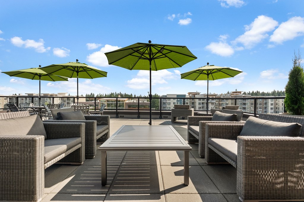 A patio with couches, tables and umbrellas.