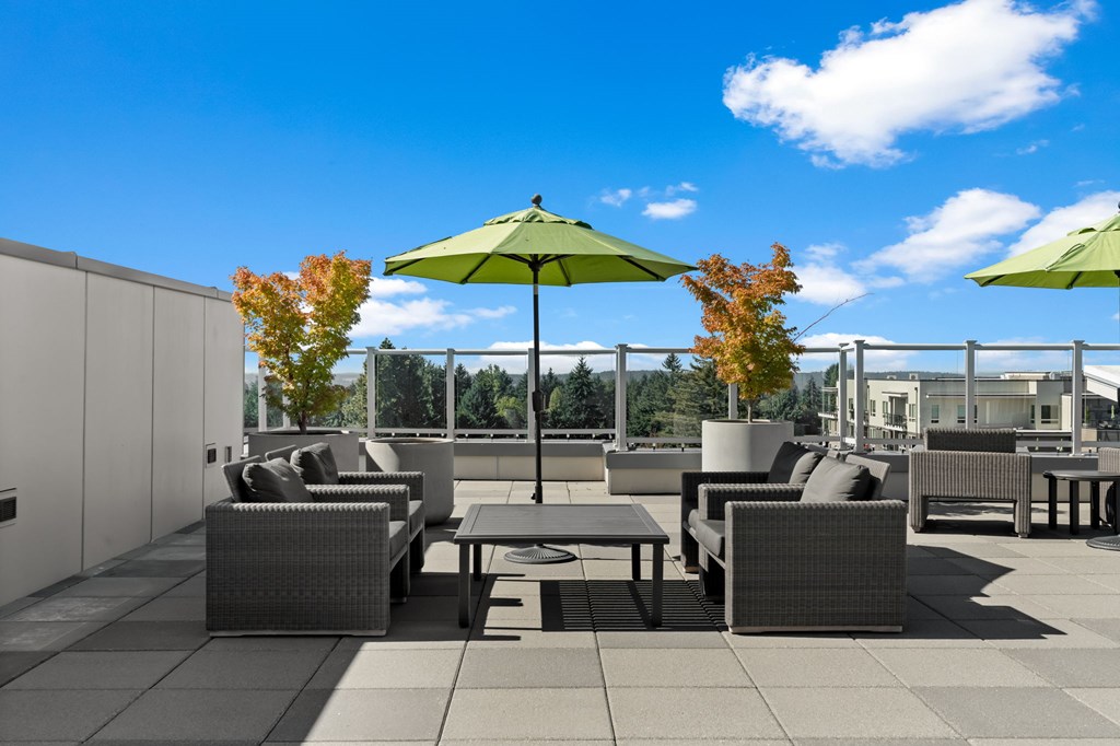 A patio with grey furniture and green umbrellas.