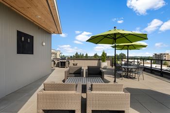 A patio with a green umbrella and chairs.