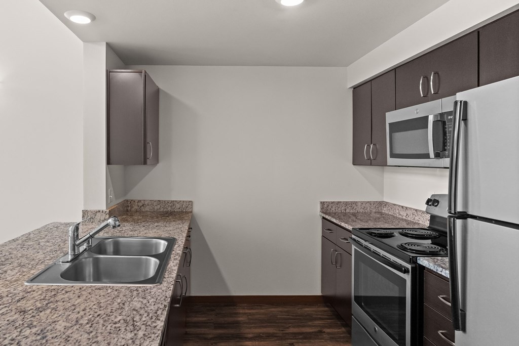 A kitchen with a sink, stove, and refrigerator.