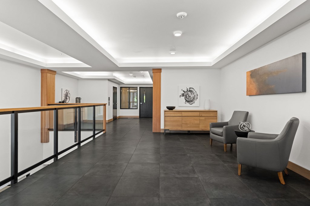 A black tiled floor in a modern room with a wooden railing and a grey chair.