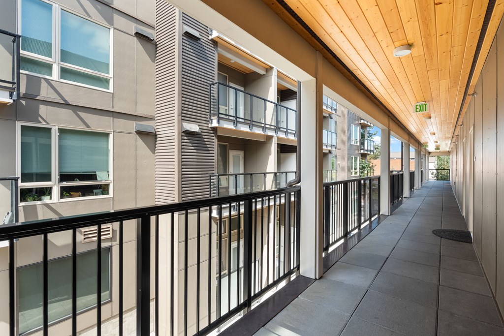 A long hallway with a black railing and a wooden ceiling.