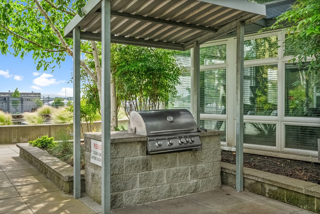 A BBQ grill is under a shelter on a patio.