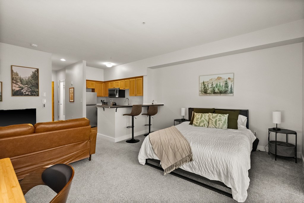 A bedroom with a bed, chair, and painting on the wall.