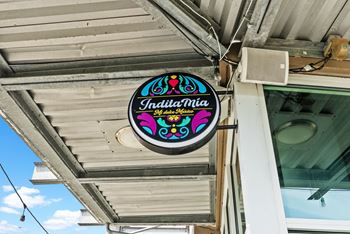 A sign for Indulge Mia hangs from a building.