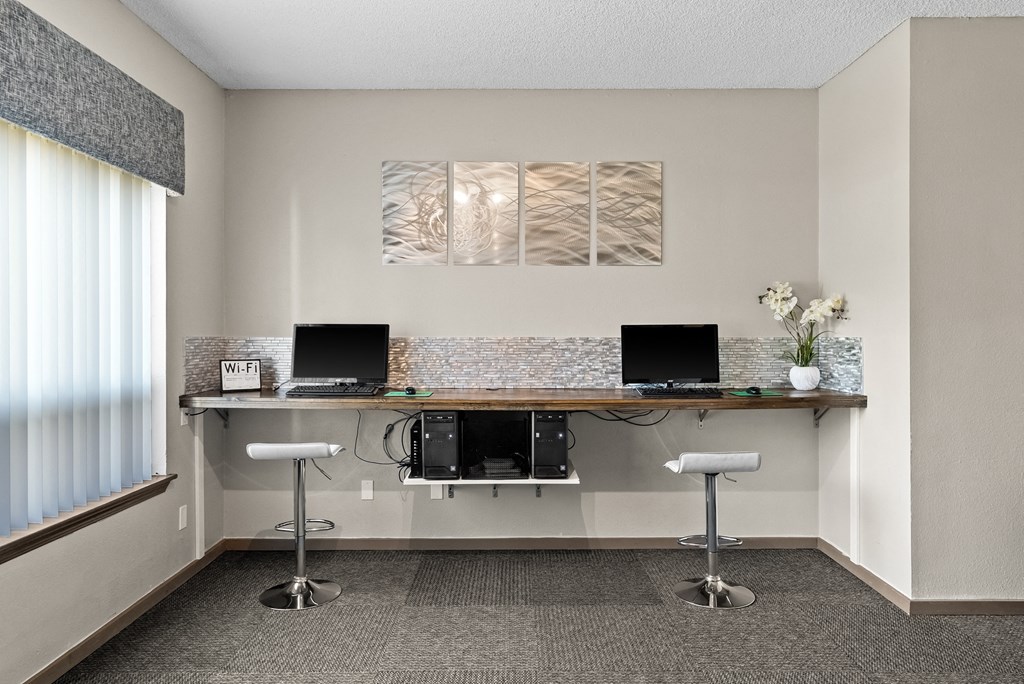 two computers sitting on a long desk in a room