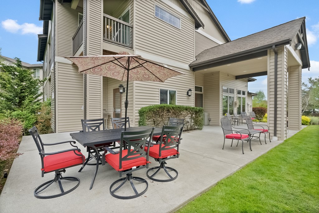 a patio with a table and chairs in front of a house