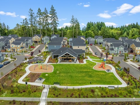 A park with a playground and a slide in the middle of a residential area.
