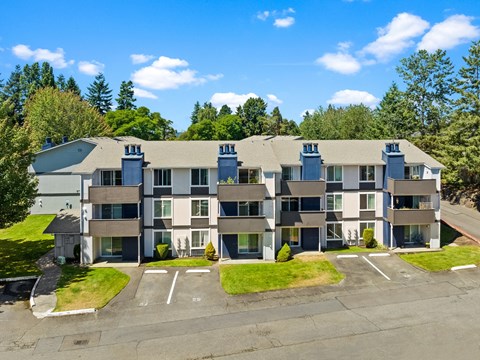 an aerial view of an apartment building with a parking lot and grass