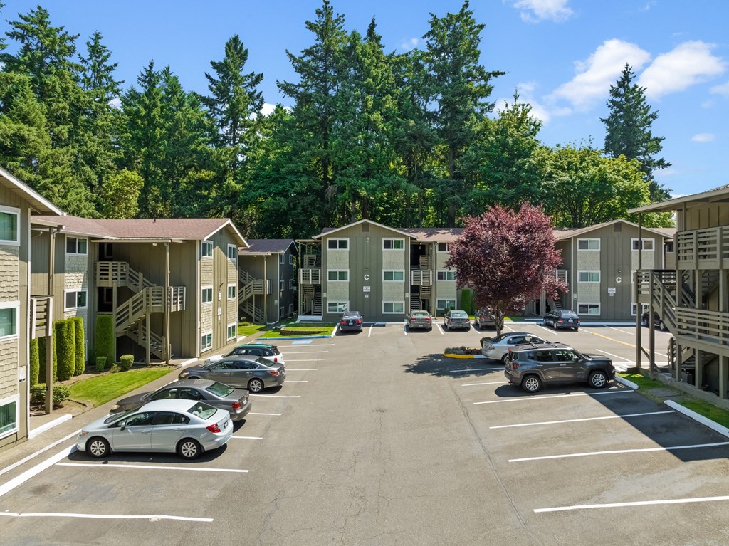 an empty parking lot in front of an apartment complex with cars parked
