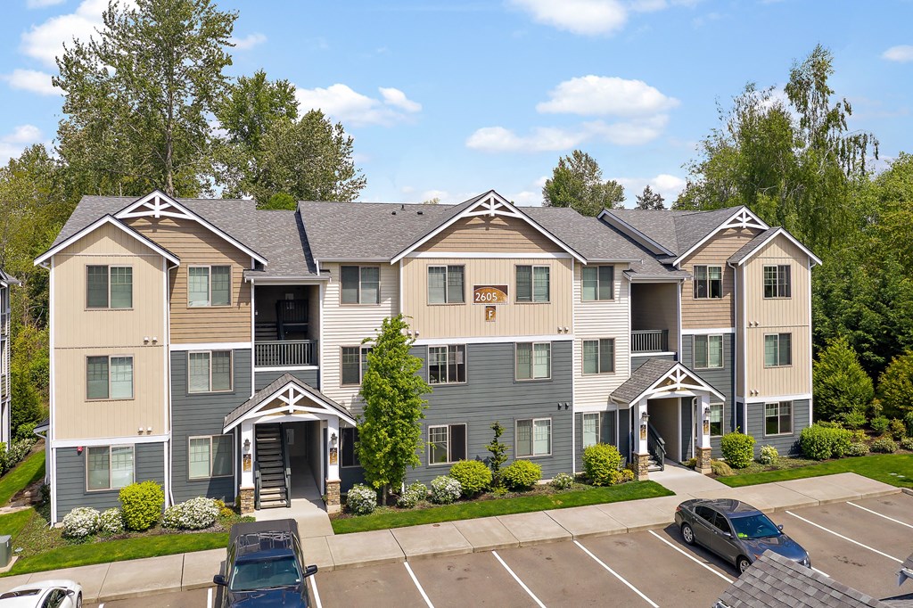 the view of an apartment building with parking lot and trees