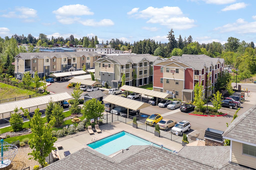 an aerial view of a pool and apartments in a parking lot