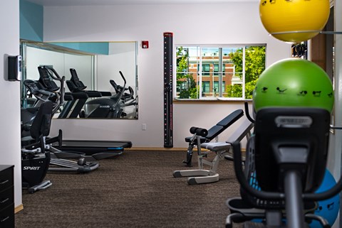 a gym with treadmills and exercise equipment in a room with a window
