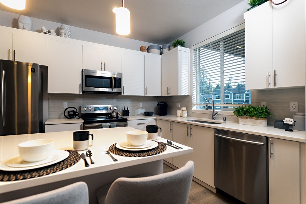 an open kitchen with a large window and a table with two cups on it