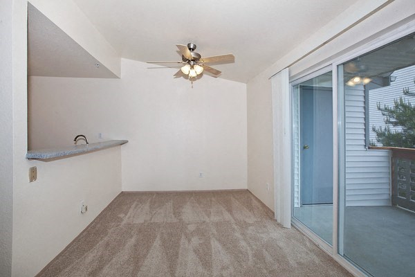 an empty living room with a ceiling fan and a sliding glass door