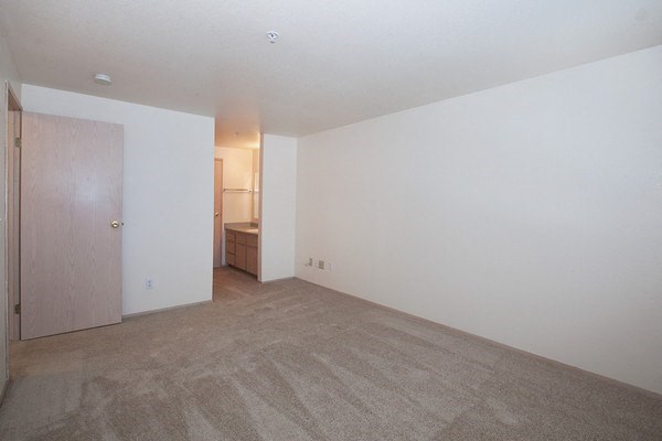 an empty living room with a door to a bathroom