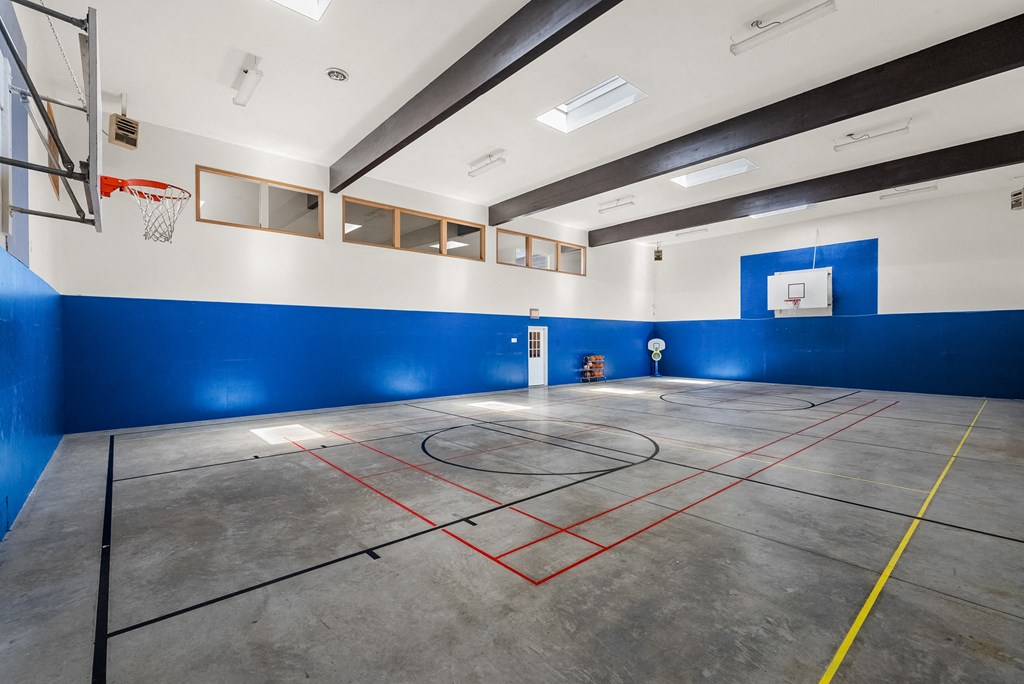 a basketball court in a gym with blue walls and a basketball hoop
